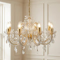 Marie Therese 8-light brass and clear crystal chandelier with teardrop droplets against a paneled wall.