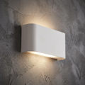 Modern white curved rectangular wall light shining light up and down on a textured concrete wall.