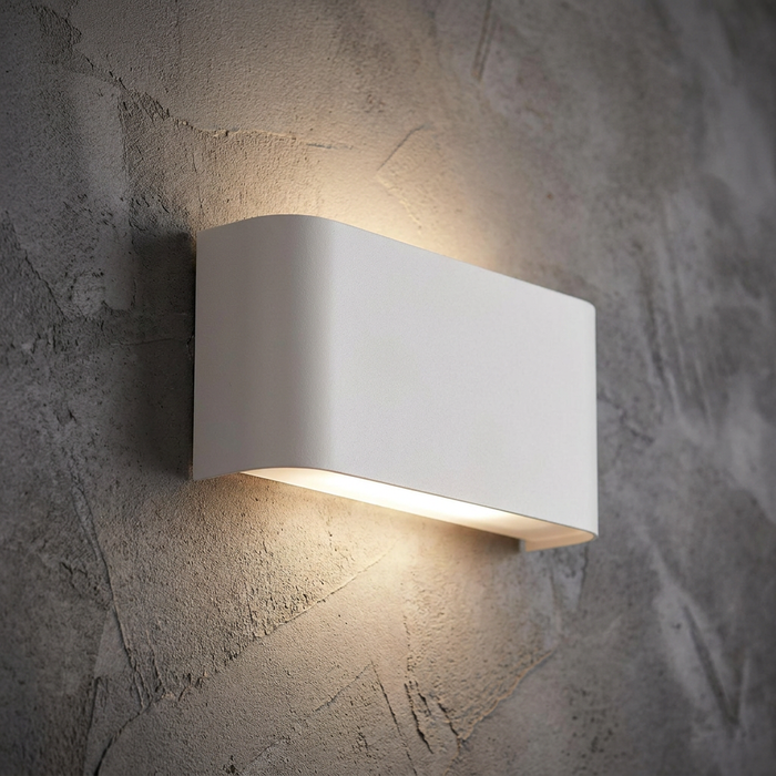 Modern white curved rectangular wall light shining light up and down on a textured concrete wall.