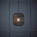 Mathias adjustable ceiling pendant featuring a dark bamboo cage shade and glowing bulb against a paneled wall.