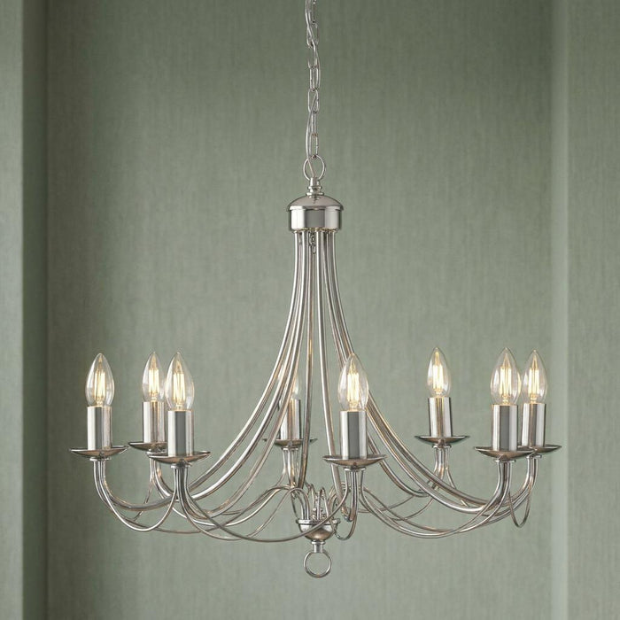 Eight-light satin silver chandelier with elegant curved arms and candle bulbs against a soft green textured wall.