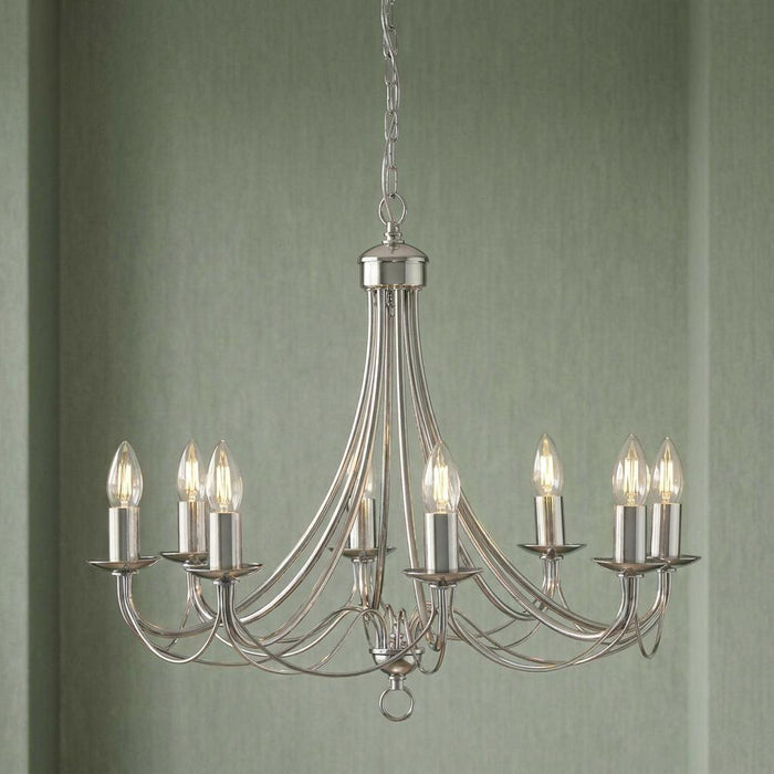 Maypole 8-light satin silver chandelier with elegant curved arms and candle bulbs against a green wall.