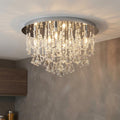 Elegant chrome flush ceiling light with cascading crystal beads and pyramid drops illuminating a room.