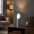 Mini antique chrome uplighter on a wooden sideboard, casting a warm glow against a grey wall in a living room.