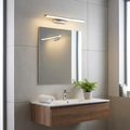 Modern chrome linear wall light mounted above a bathroom mirror, illuminating a sleek vanity area.