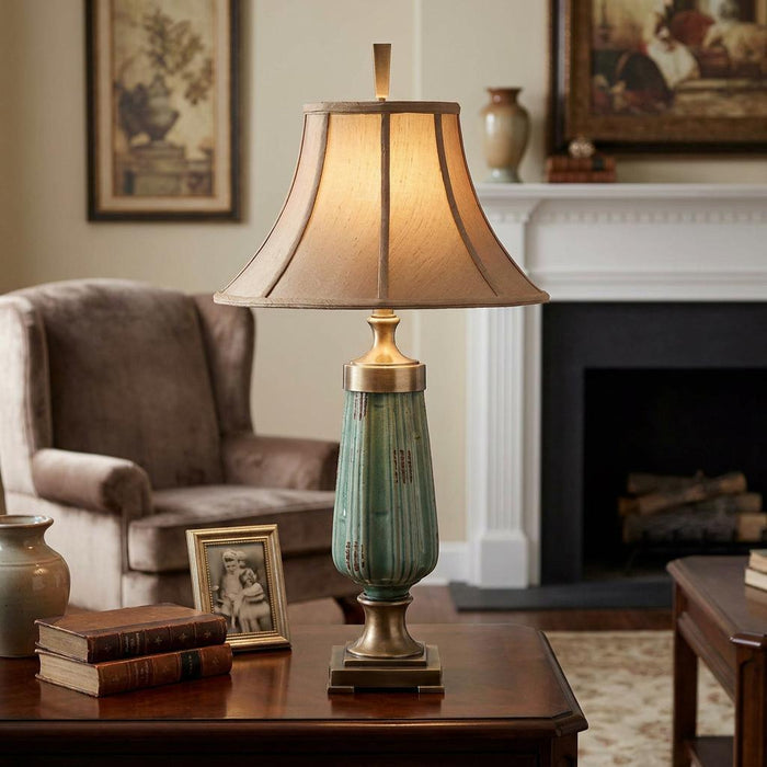 Green fluted ceramic table lamp with a warm beige bell shade on a wooden table in a cozy traditional living room.