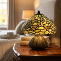 Tiffany table lamp with a green stained glass butterfly shade on a wooden nightstand in a cozy bedroom.