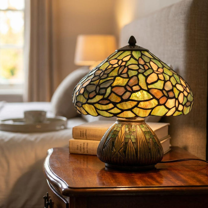 Tiffany table lamp with a green stained glass butterfly shade on a wooden nightstand in a cozy bedroom.