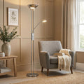 Chrome mother and child floor lamp with warm glow, standing next to a grey armchair in a modern neutral living room.