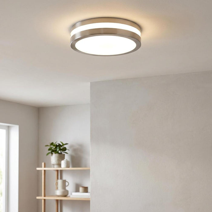 Modern circular silver flush mount ceiling light with glowing panels in a neutral-toned room.