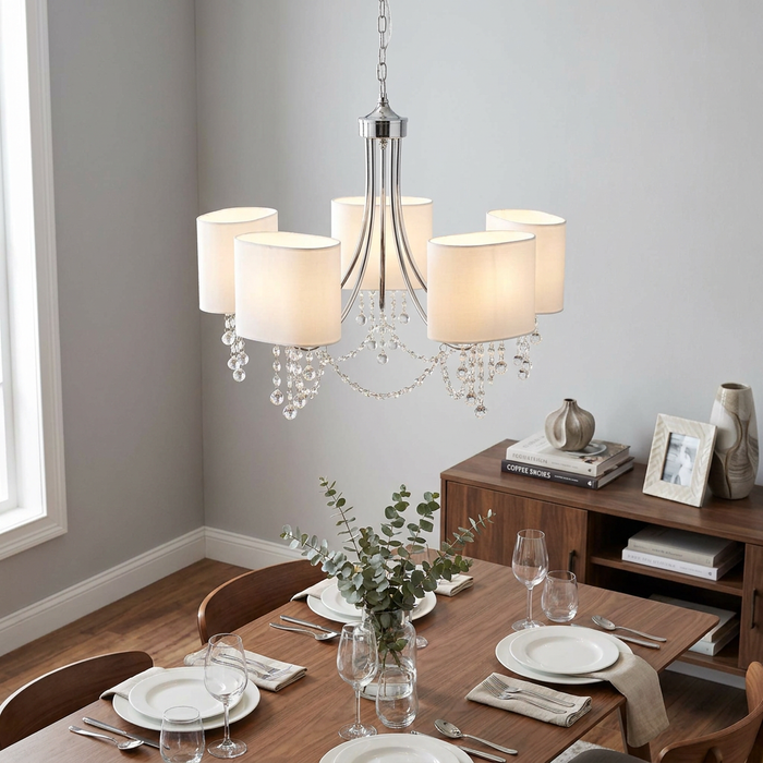 Nina 5-light chrome and crystal pendant with white shades hanging above a set dining table in a modern room.