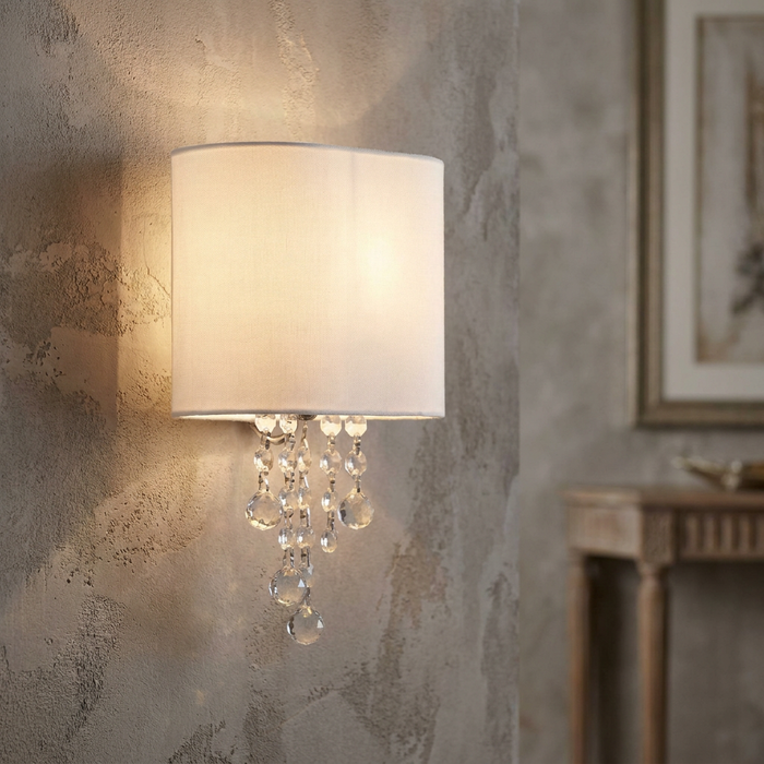 Nina Light Chrome & Crystal wall light with a white fabric shade and cascading crystals on a textured wall.