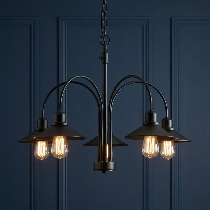 Oaks Dalvik 5-light black chandelier with conical shades and vintage filament bulbs against a dark blue wall.