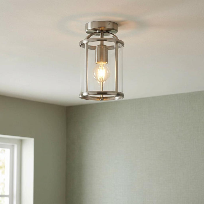 Antique chrome cylinder flush ceiling light with clear glass panels, illuminated in a modern room setting.