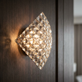 Square crystal wall light with faceted glass grid glowing on a dark wood surface.