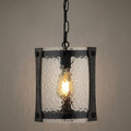 Black hanging lantern with textured glass panels and a single glowing light bulb against a neutral wall.