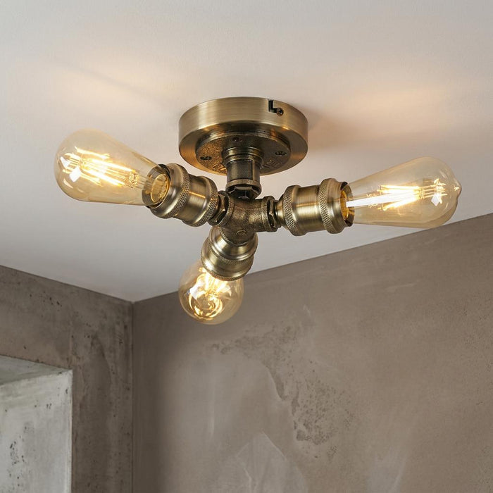Industrial 3-light antique brass flush ceiling fixture with exposed filament bulbs.