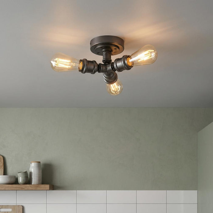 Industrial 3-light gun metal flush ceiling fixture with warm Edison bulbs in a modern kitchen setting.