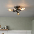 Industrial 3-light gun metal flush ceiling fixture with warm Edison bulbs in a modern kitchen setting.