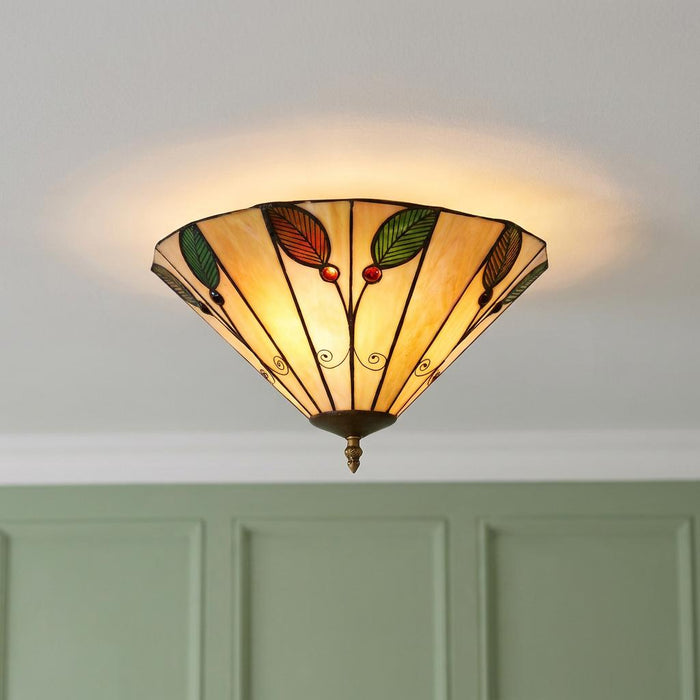 A warm Tiffany-style flush ceiling light with leaf patterns and red jewels mounted on a white ceiling.