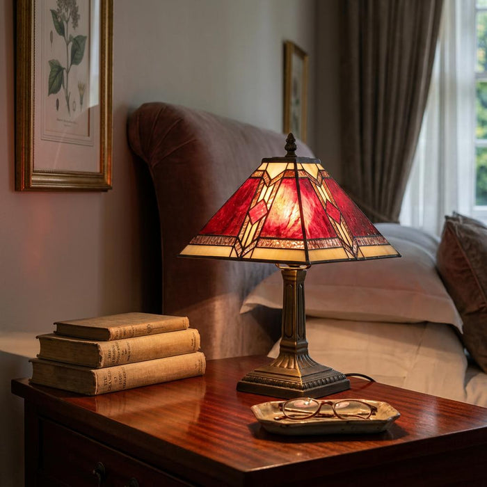 Oaks Lighting Aztec Tiffany bedside lamp with a red geometric stained glass shade on a dark wood nightstand.