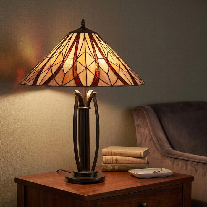 A Tiffany-style table lamp with a cream and red geometric shade glows on a wooden side table.