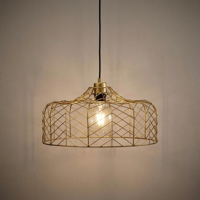 Matt gold wire cage ceiling pendant light with a glowing bulb hanging against a plain beige wall.