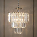 Three-tier clear acrylic and chrome pendant light with glowing bulbs hanging against a beige paneled wall.