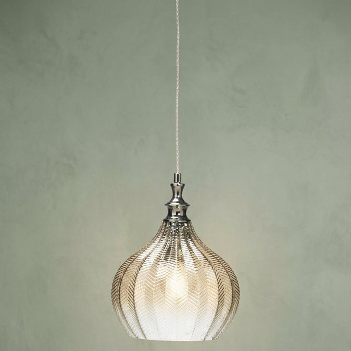 Cognac textured glass pendant light with chrome accents hanging against a muted green background.