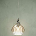 Cognac textured glass pendant light with chrome accents hanging against a muted green background.
