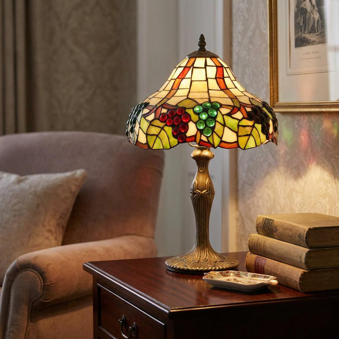 Tiffany table lamp with a stained glass grapevine shade on a dark wood table in a classic interior.