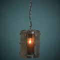 Rustic wood and metal cylinder pendant light with a mesh cage and glowing bulb against a dark teal wall.