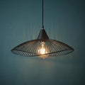 Black wireframe pendant light with a glowing filament bulb against a dark teal wall.
