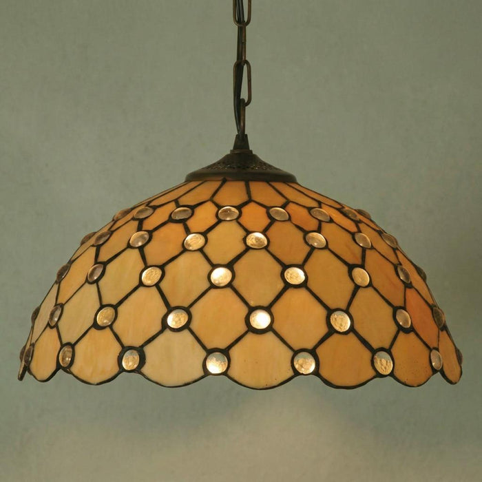 Jewel Tiffany pendant light with honey-toned stained glass, circular jewels, and diamond leading against a plain wall.