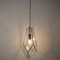 Faceted geometric glass pendant light with a black metal frame and glowing bulb against a neutral wall.