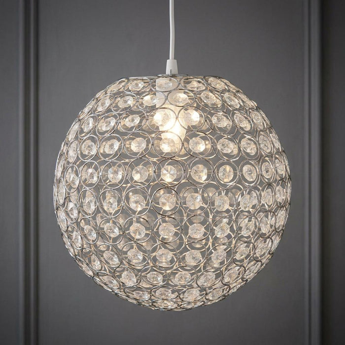 Spherical chrome pendant light with acrylic crystal buttons illuminated against a grey wall.