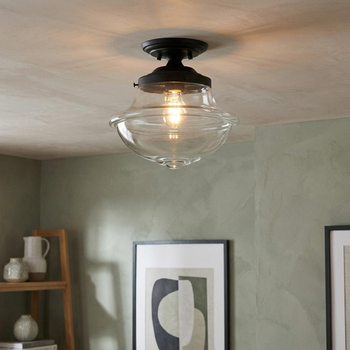 Oaks Lighting Lars clear glass and black flush ceiling light glowing in a room with green walls.