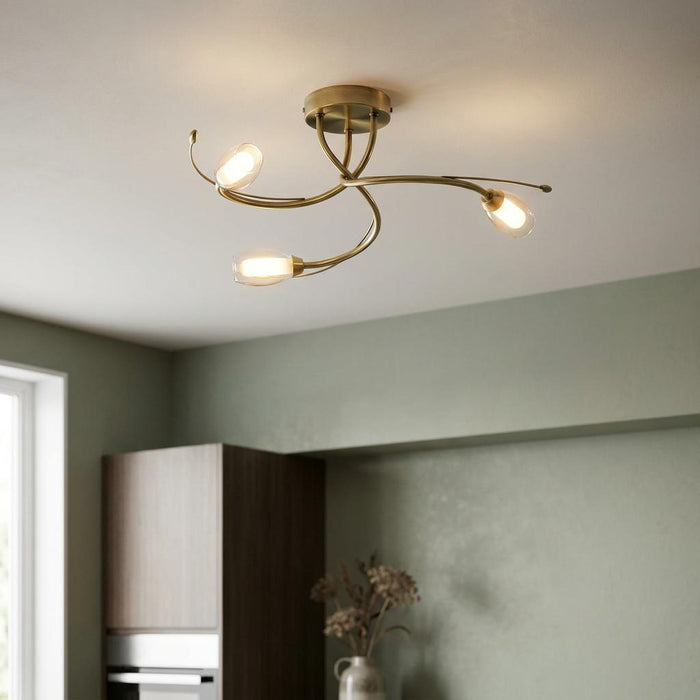 Oaks Lighting Pandora 3-light antique brass semi-flush ceiling light with curved arms in a modern kitchen setting.