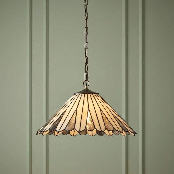 A Tiffany-style pendant light with a cream scalloped shade hangs against a light green paneled wall.