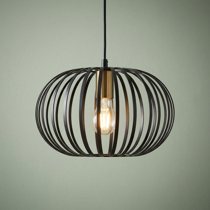 Black metal wire cage pendant light with a brass socket and a glowing light bulb.