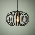 Black metal wire cage pendant light with a brass socket and a glowing light bulb.