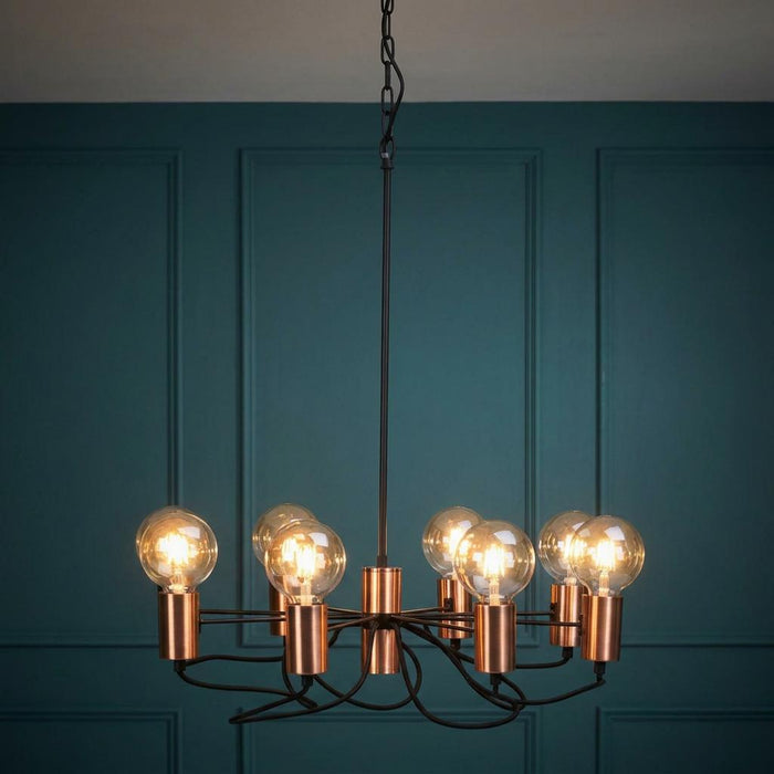 Oaks Lighting Tala 8-light matt copper chandelier with exposed bulbs against a dark teal paneled wall.
