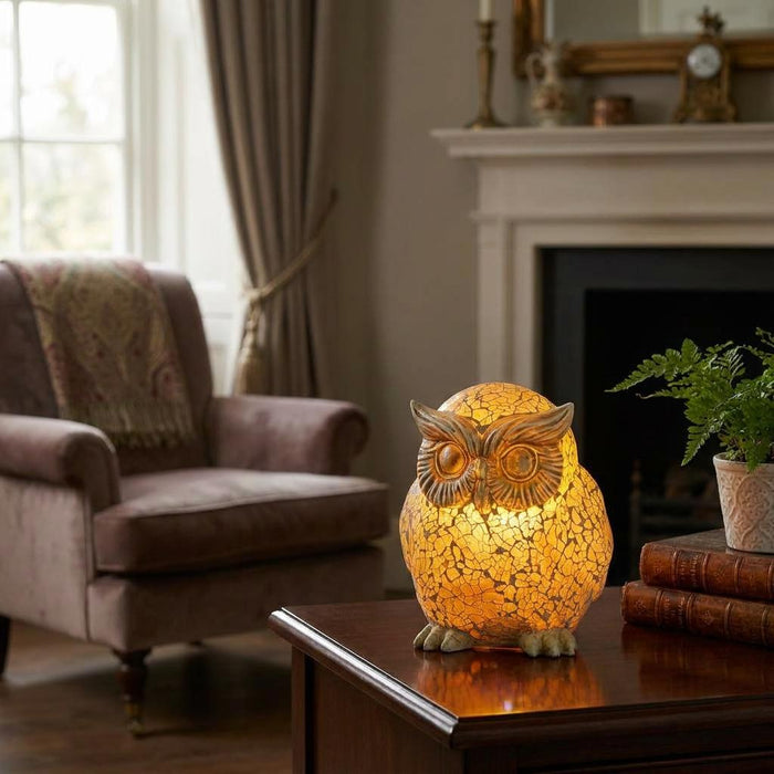 Amber mosaic glass owl novelty lamp glowing on a wooden table in a cozy living room setting.