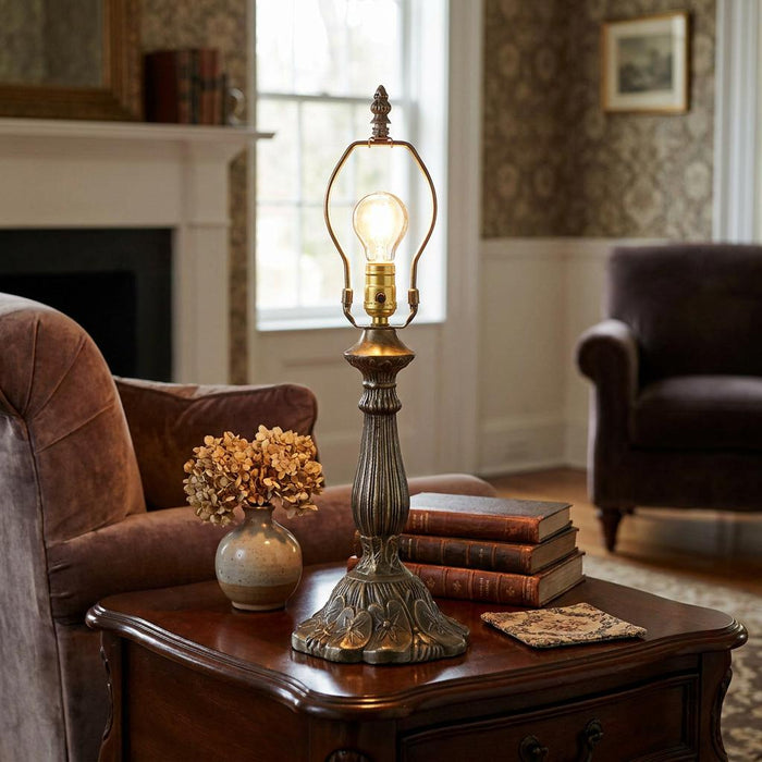 Ornate bronze lamp base with a glowing bulb sits on a wooden side table in a cozy living room.