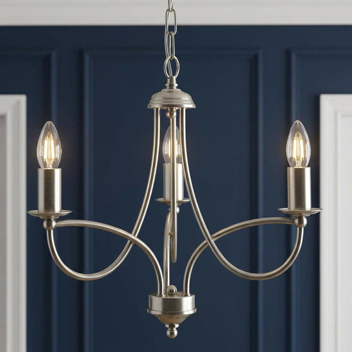 Antique chrome three-light chandelier with looping arms against a navy blue paneled wall.