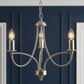 Antique chrome three-light chandelier with looping arms against a navy blue paneled wall.