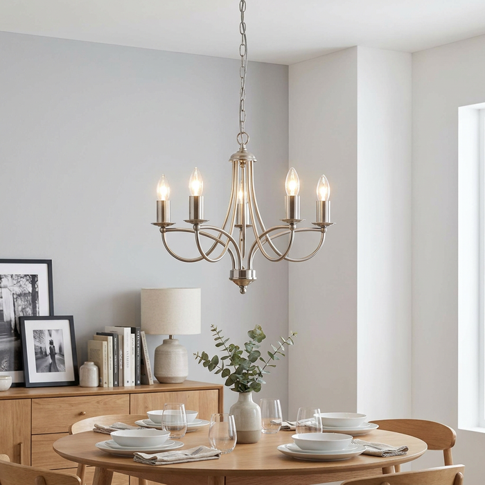 Antique chrome 5-light chandelier with curved arms hanging over a set wooden dining table in a neutral room.