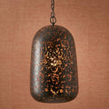 Black and copper domed pendant light with perforated cutouts hanging against a textured tan wall.