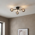 Modern black semi-flush ceiling light with three smoked glass globes on a white ceiling.