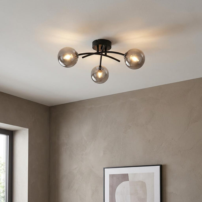 Modern black semi-flush ceiling light with three smoked glass globes on a white ceiling.